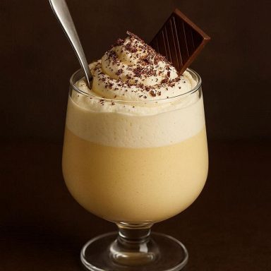 Cremiger Löffel‑Eierlikör im Glas, geschichtet mit Mascarpone und Sahne, dekoriert mit Schokolade für ein elegantes Dessert.
