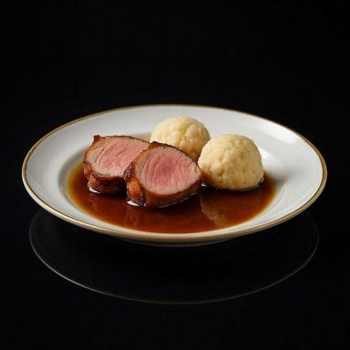 Zartes Schweinefilet und fluffige Knödel auf einem Teller, überzogen mit glänzender Bratensauce, warm angerichtet und appetitlich serviert.