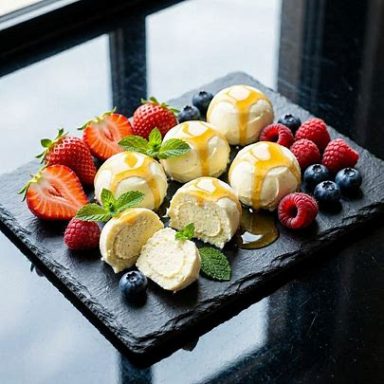 Cremige Skyr‑Vanille‑Trüffel mit frischen Erdbeeren, Himbeeren und Blaubeeren, veredelt mit Honig‑Zitronen‑Glasur und Minze.