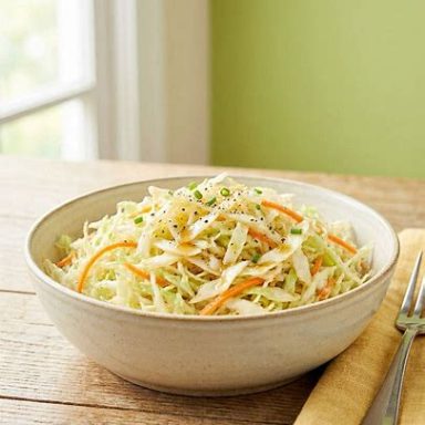 Fein geschnittener Krautsalat mit Apfelessig, leicht glänzend, frisch geknetet und serviert in einer Schüssel als knackige Beilage