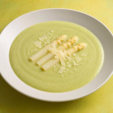 Cremige Spargelsuppe mit Parmesan, fein püriert, hell und samtig serviert in einer Schale, dekoriert mit Spargelspitzen und Parmesan.