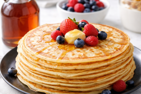 Goldene Buttermilch‑Pfannkuchen auf einem Teller, locker und weich, frisch gebraten mit Butter und leicht gebräunten Rändern.